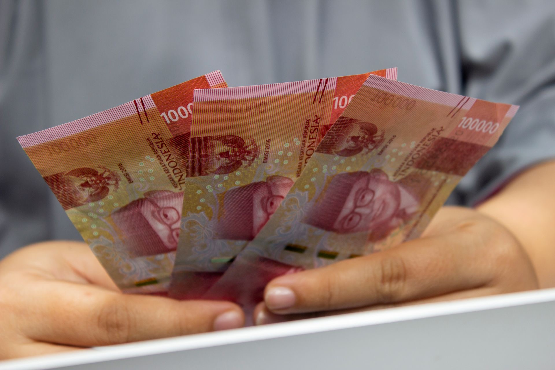 Tangan memegang uang kertas rupiah Indonesia — simbol pembahasan Rupiah Digital, stablecoin rupiah, USDT, IDRX, dan IDRT bagi investor kripto Indonesia 2026